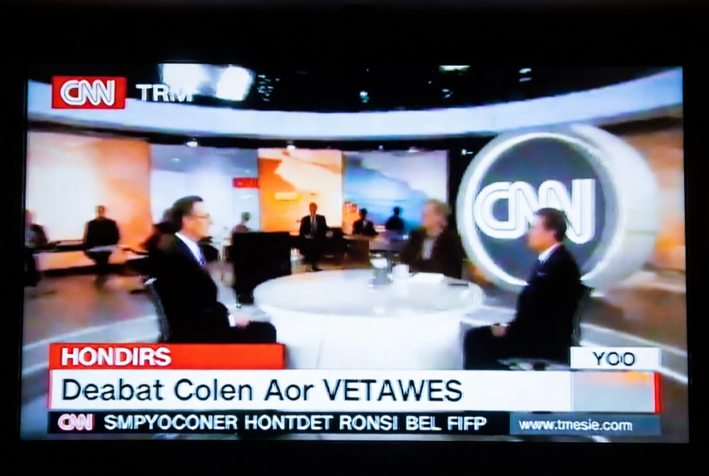 Why Fit-to-Screen Isn’t the Solution: Preserving Original Video Quality 3 Screenshot of a news broadcast with a stretched fit-to-screen SD video showing distorted logos, blurred text, and misaligned graphics.